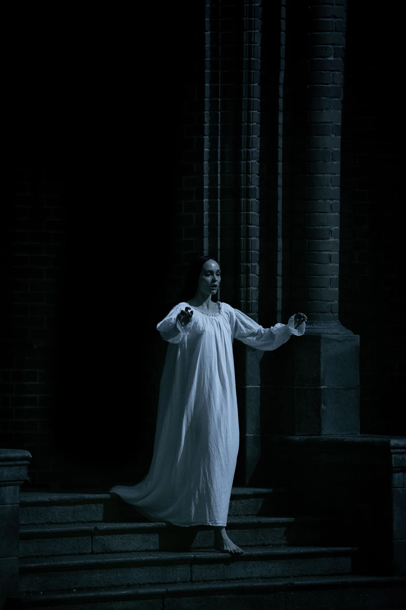 Nosferatu (2024): Ellen in a white dress on a dark stone staircase